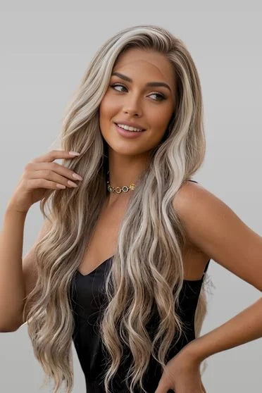 Woman with long, wavy blonde hair posing against a plain background