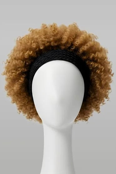 Brown curly wig on a mannequin head against a gray background
