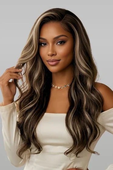Woman with long, wavy hair holding a section of it against a neutral background